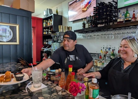 Two people at Oscar's bar behind the patterned counter